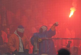 Ein vermummter Anhänger des FC Hansa Rostock wirft mit Keramik-Teilen (rechts).