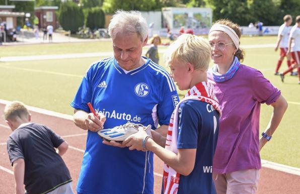 Olaf Thon (links) signiert einen Fußballschuh.