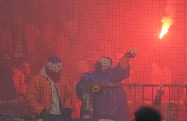 Ein vermummter Anhänger des FC Hansa Rostock wirft mit Keramik-Teilen (rechts).