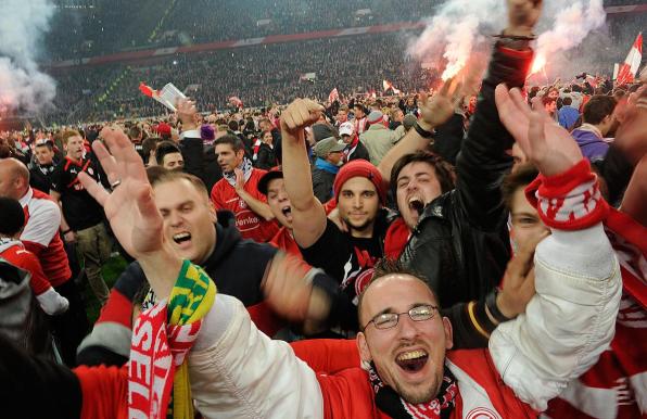 Fans von Fortuna Düsseldorf jubeln auf dem Platz.